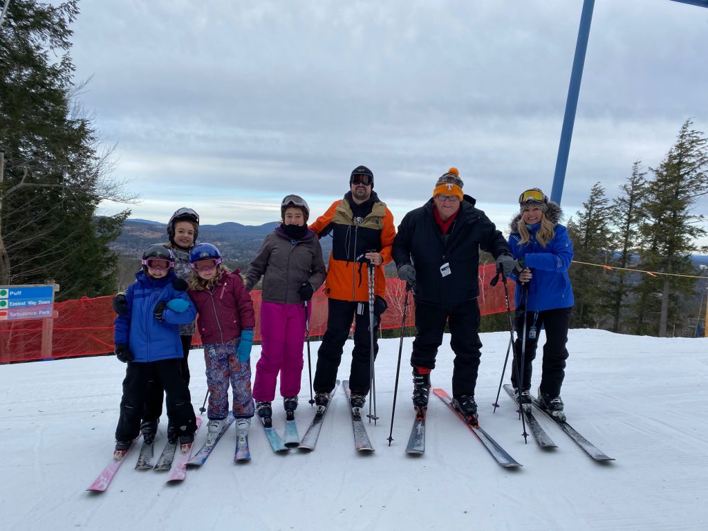 a group skiing and posing on top of the skii lift