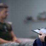 a blurry photo of a man looking away from a man offscreen who can only be seen holding a clipboard