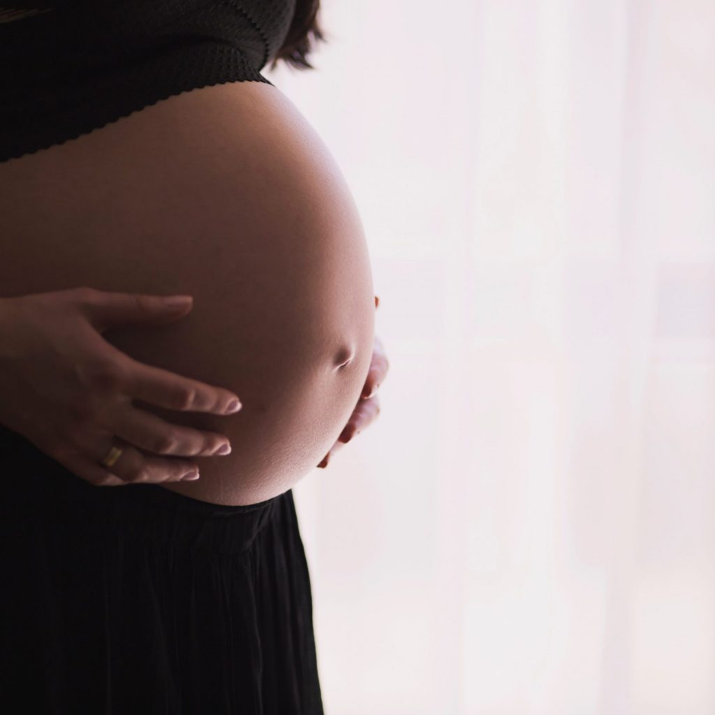 pexels-freestocksorg-57529 a pregnant woman in her third trimester is holding her stomach.